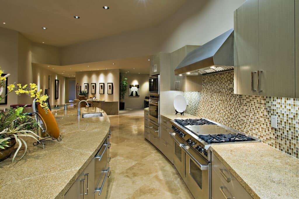 Modern kitchen interior with granite countertops and mosaic tile backsplash — a reminder that vinegar can damage natural stone and grout surfaces.
