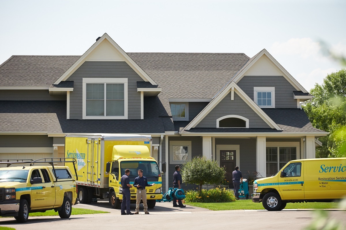 ServiceMaster Restoration by Simons truck and team in front of a house. Ready to provide water damage and fire damage restoration services.