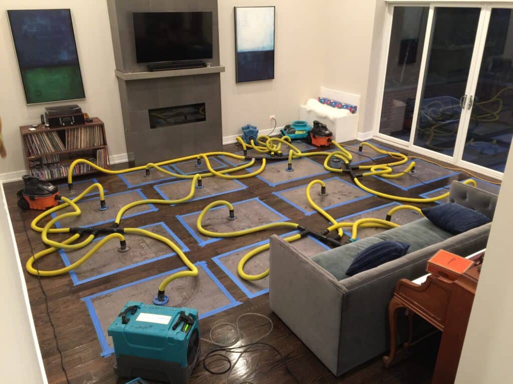 Injectidry and Dri-Eaz systems drying water-damaged hardwood floors in a Chicago living room