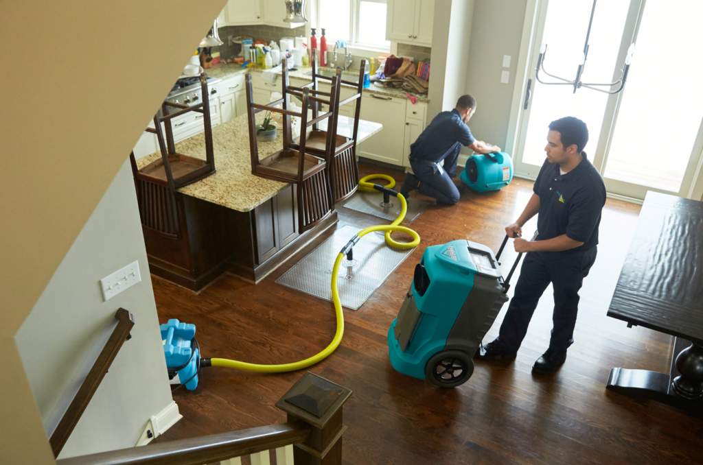 ServiceMaster team using drying equipment to rescue water-damaged hardwood floors in a residential Chicago kitchen